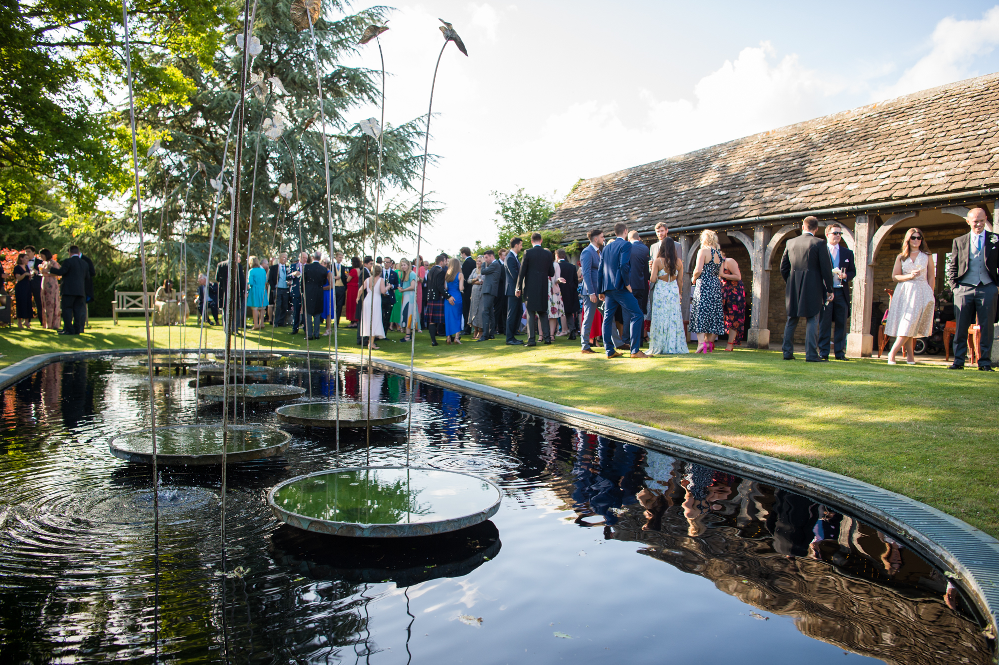 Guests enjoying the wedding celebrations in the gardens of Whatley Manor